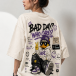 Woman wearing Luri Bad Day Who Cares graphic oversized t-shirt — cream unisex streetwear tee with graffiti duck character, "Bad Day? Who Cares!" grunge text, smiley faces and purple sticker graphics, back view