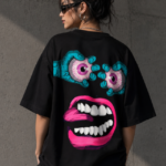 Woman wearing Luri Chaos Face graphic oversized t-shirt — black unisex art tee with surrealist monster face print in teal and hot pink, back view, oversized fit