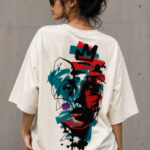 Woman wearing Luri Crowned Face graphic oversized t-shirt — cream unisex street art tee with neo-expressionist crowned face print in teal, red and black, back view