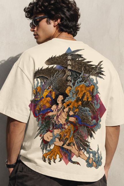 Man wearing Luri Garuda Mythology graphic oversized t-shirt — cream unisex tee with detailed ukiyo-e style Garuda divine eagle descending with multi-armed deity, Sanskrit script and gold detail, back view