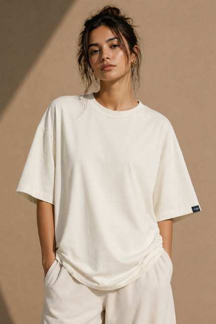 Woman wearing Luri Signature Oversized Tee in off-white — premium unisex 260 GSM Supima Cotton t-shirt, front view, relaxed oversized fit with matching cream co-ord set