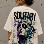 Woman wearing Luri Solitary Star graphic oversized t-shirt — cream unisex streetwear tee with grunge classical marble statue print, star motifs and bold typography in black, purple and teal, back view