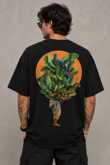 Man wearing Luri Tropical Soul graphic oversized t-shirt — black unisex tee with richly illustrated tropical figure, banana leaves and macaw parrots in an orange sun circle, back view