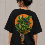 Woman wearing Luri Tropical Soul graphic oversized t-shirt — black unisex tee with illustrated botanical figure, tropical leaves and parrots on orange sun motif, back view